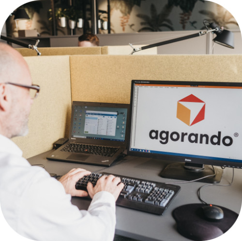 Mitarbeiter an Arbeitsplatz mit Computer im modernen Büro von Agorando