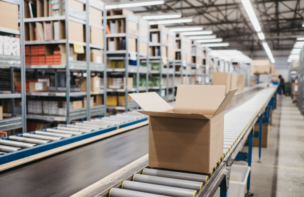 Förderband mit Versandkartons in modernem Logistikzentrum von agorando
